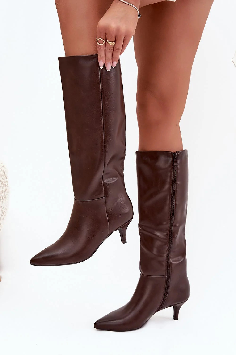 Brown pointed-toe knee-high boots with kitten heels and side zippers.