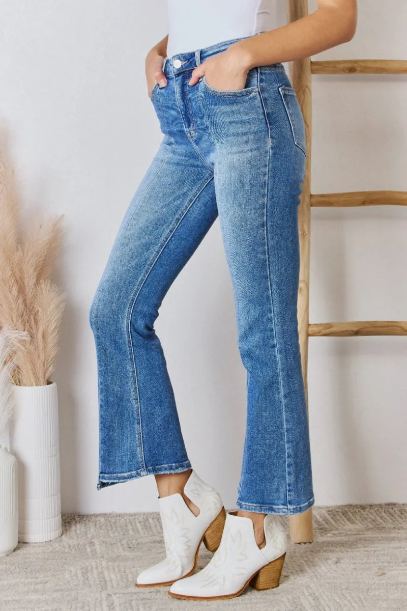 Medium wash flared jeans with a distressed texture and white cowboy boots.