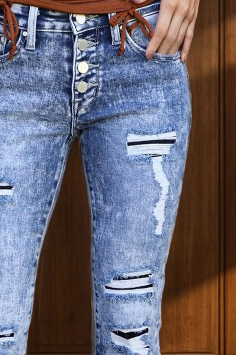 Distressed acid-wash denim jeans with button fly and ripped details.