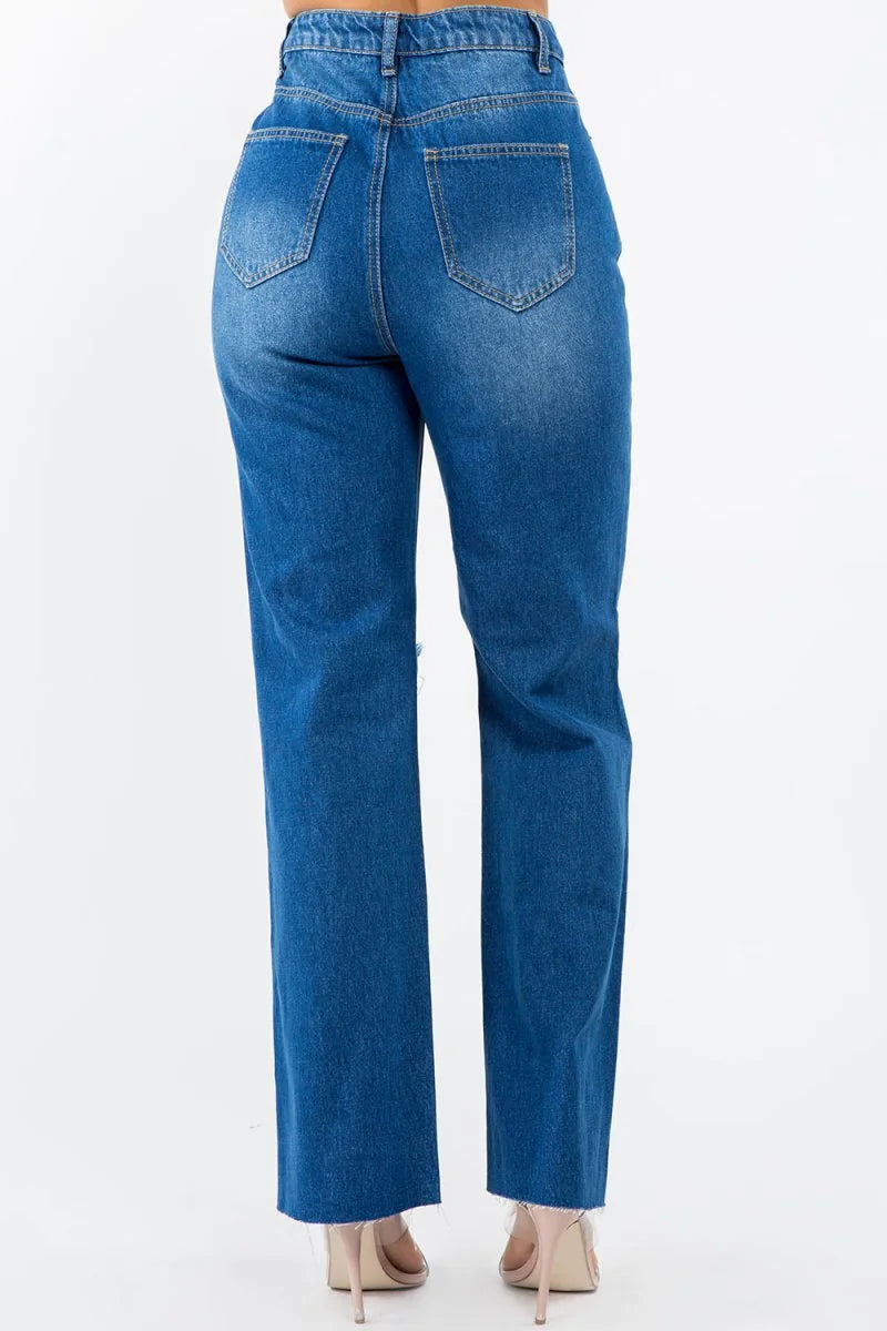 Back view of distressed blue denim jeans with a frayed hem and ripped detail.