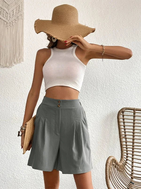 Grey pleated shorts with a high waist and button details, on a model.