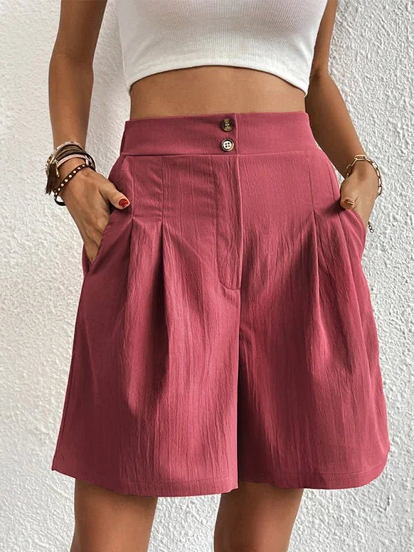 Close-up of dusty rose pleated shorts with button detail and textured fabric.