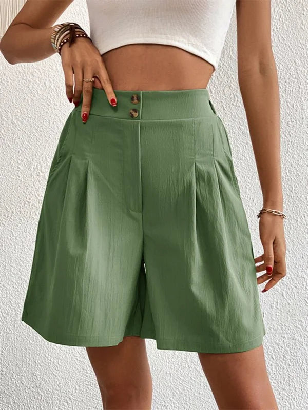 Green pleated shorts with button closure and textured fabric on model