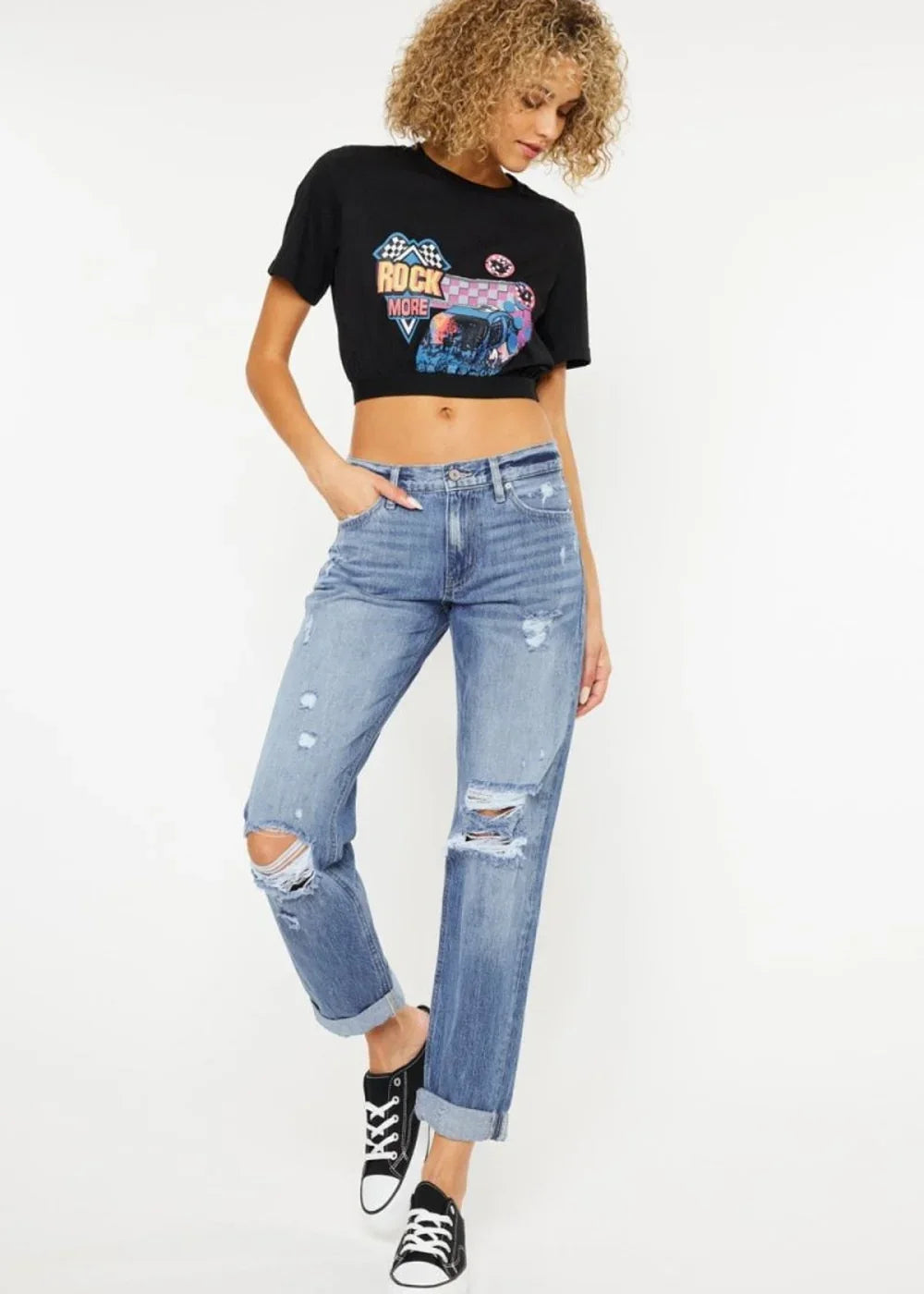 Distressed light wash denim jeans with rolled cuffs and rips, on a model.