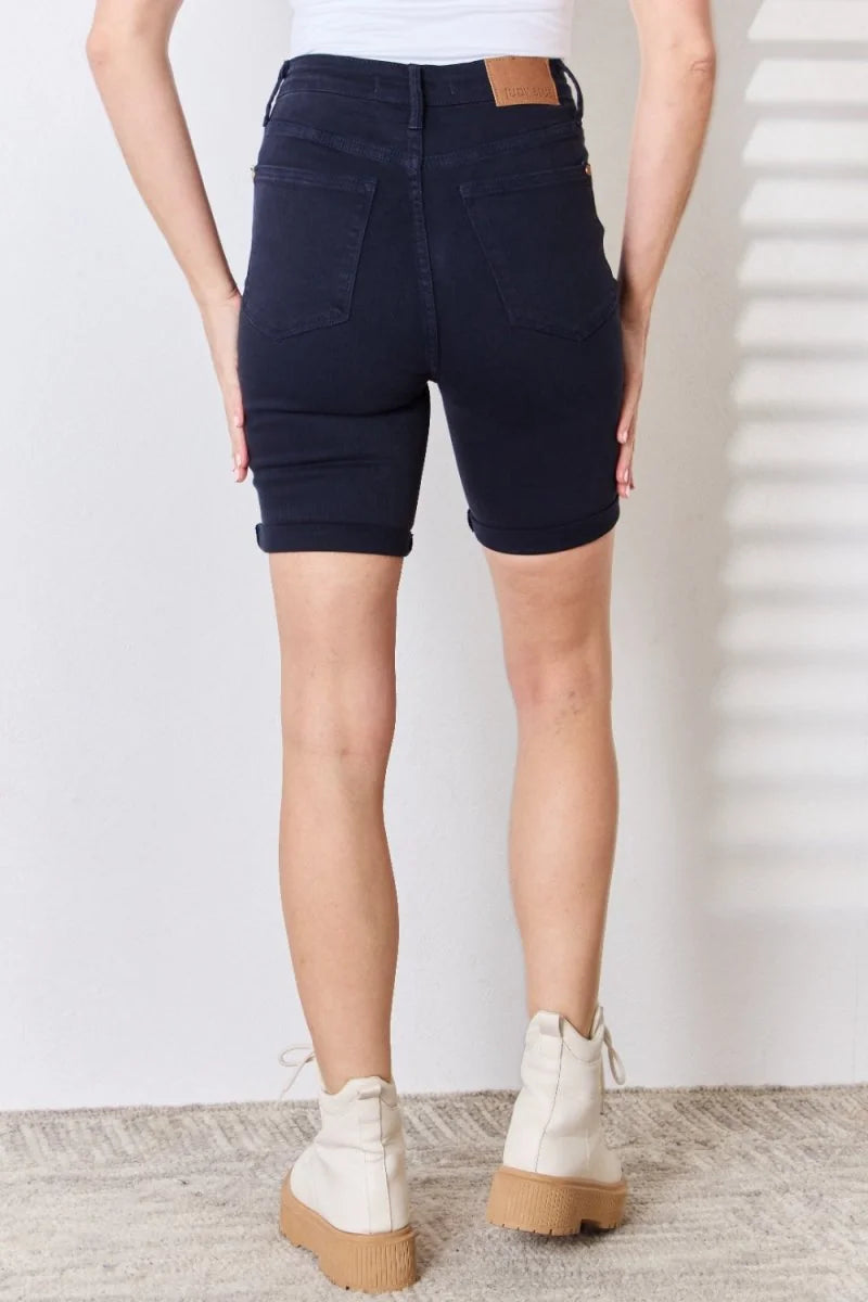 Back view of navy blue denim shorts with cuffed hems, worn by a model with cream-colored platform boots.