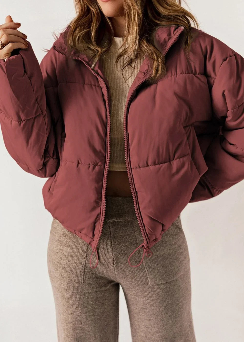 Cropped maroon puffer jacket with a full zip and textured knit pants.