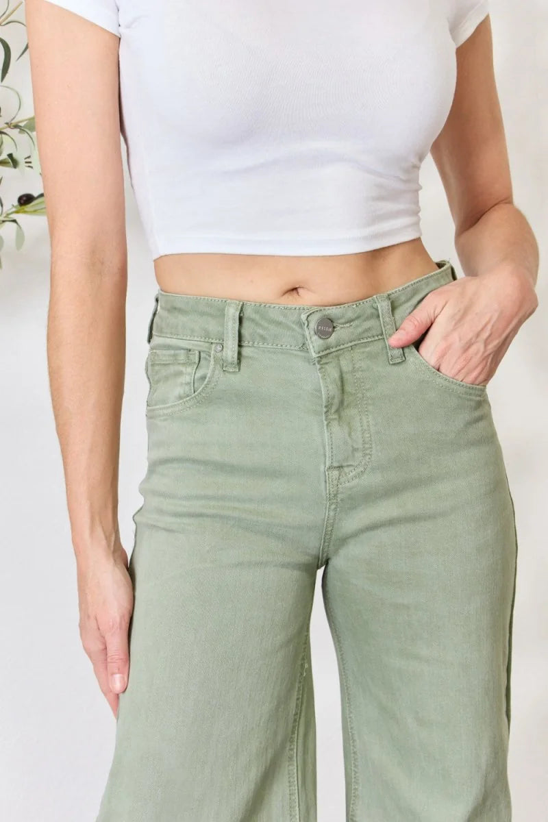 High-waisted, light green denim pants with a button closure, shown on a model.