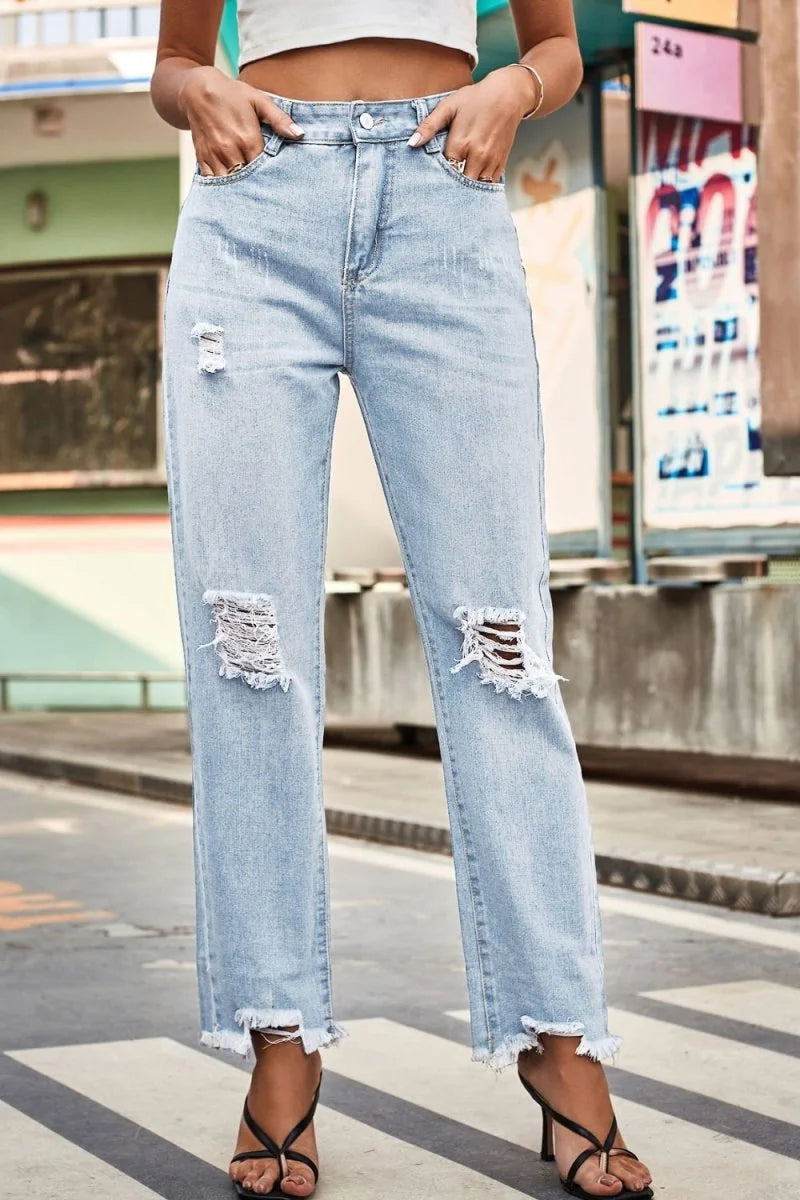Light wash distressed denim jeans with frayed hem and loose fit.