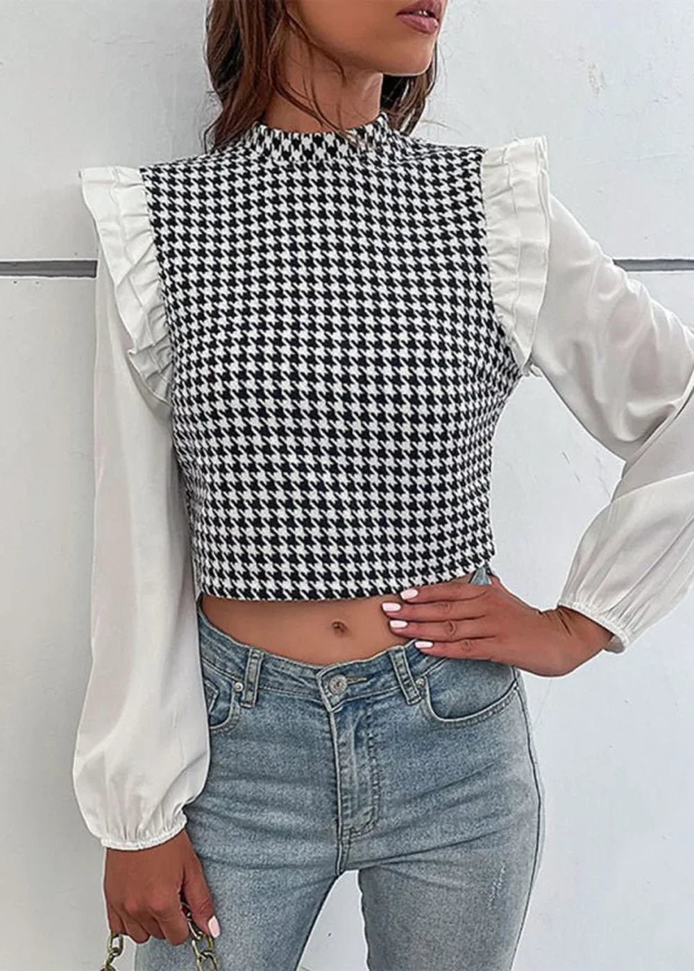 Woman in houndstooth crop top with white ruffled sleeves and blue jeans