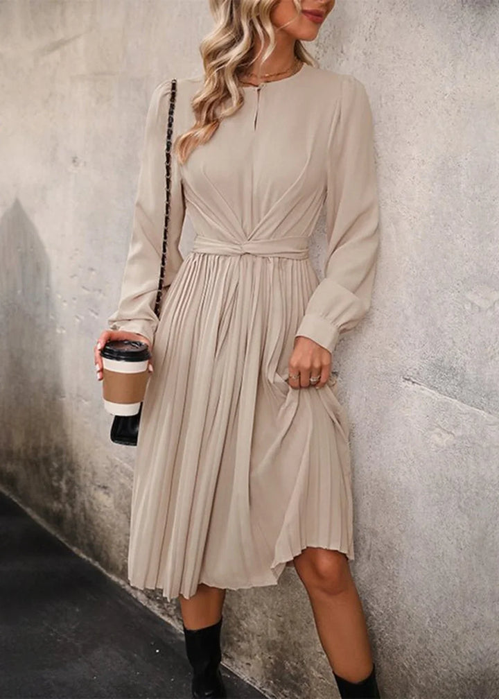 Beige pleated midi dress with ruched waist detail, worn by a model holding a coffee cup.