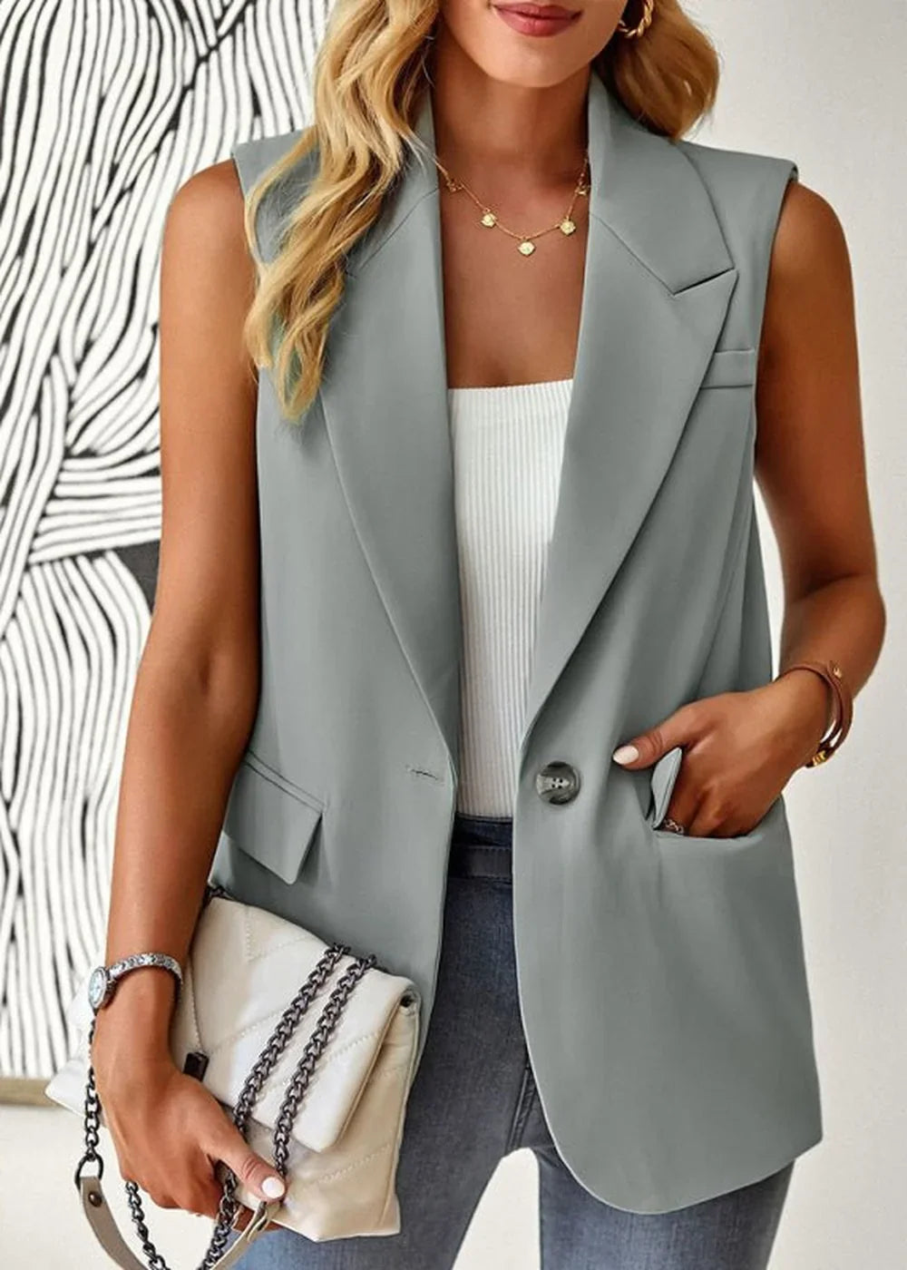 Gray sleeveless blazer with a white ribbed tank top and chain-strap handbag.