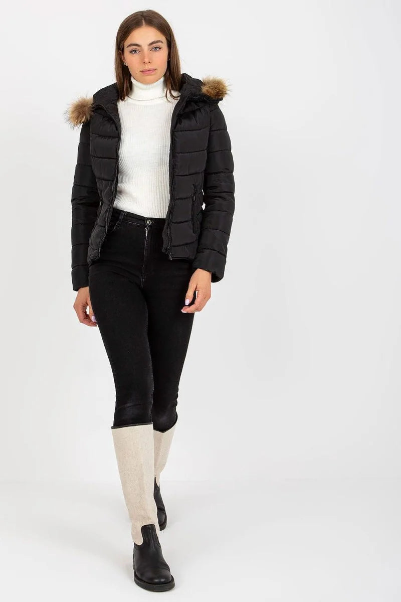 Black puffer jacket with fur-trimmed hood, worn by a model with black jeans and cream and black boots.