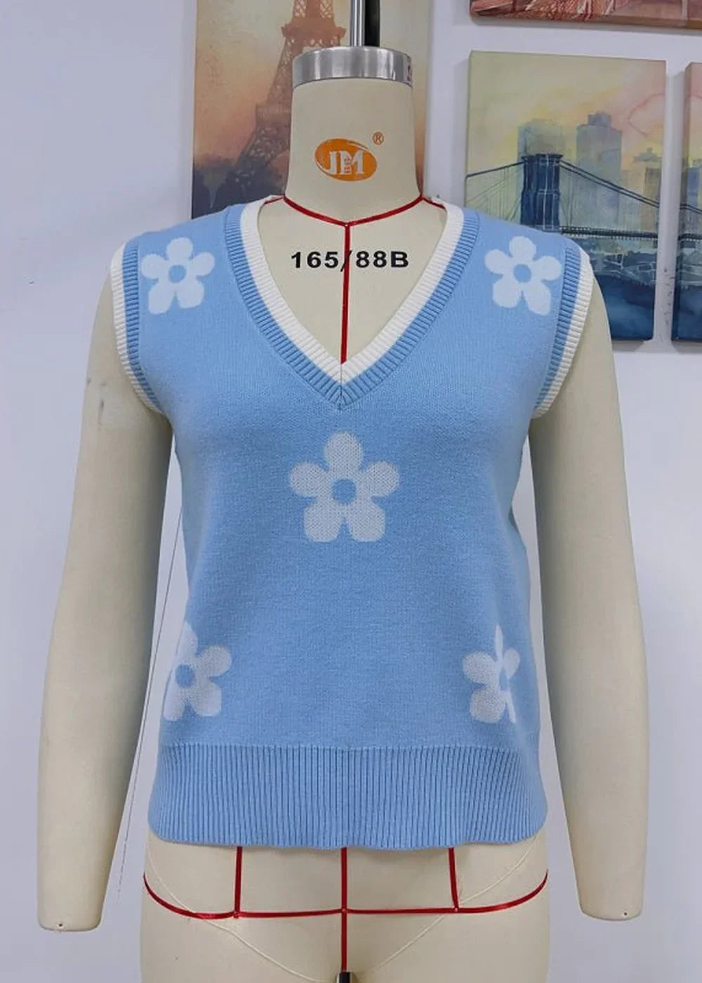 Light blue knit vest with white floral pattern and white trim, v-neck