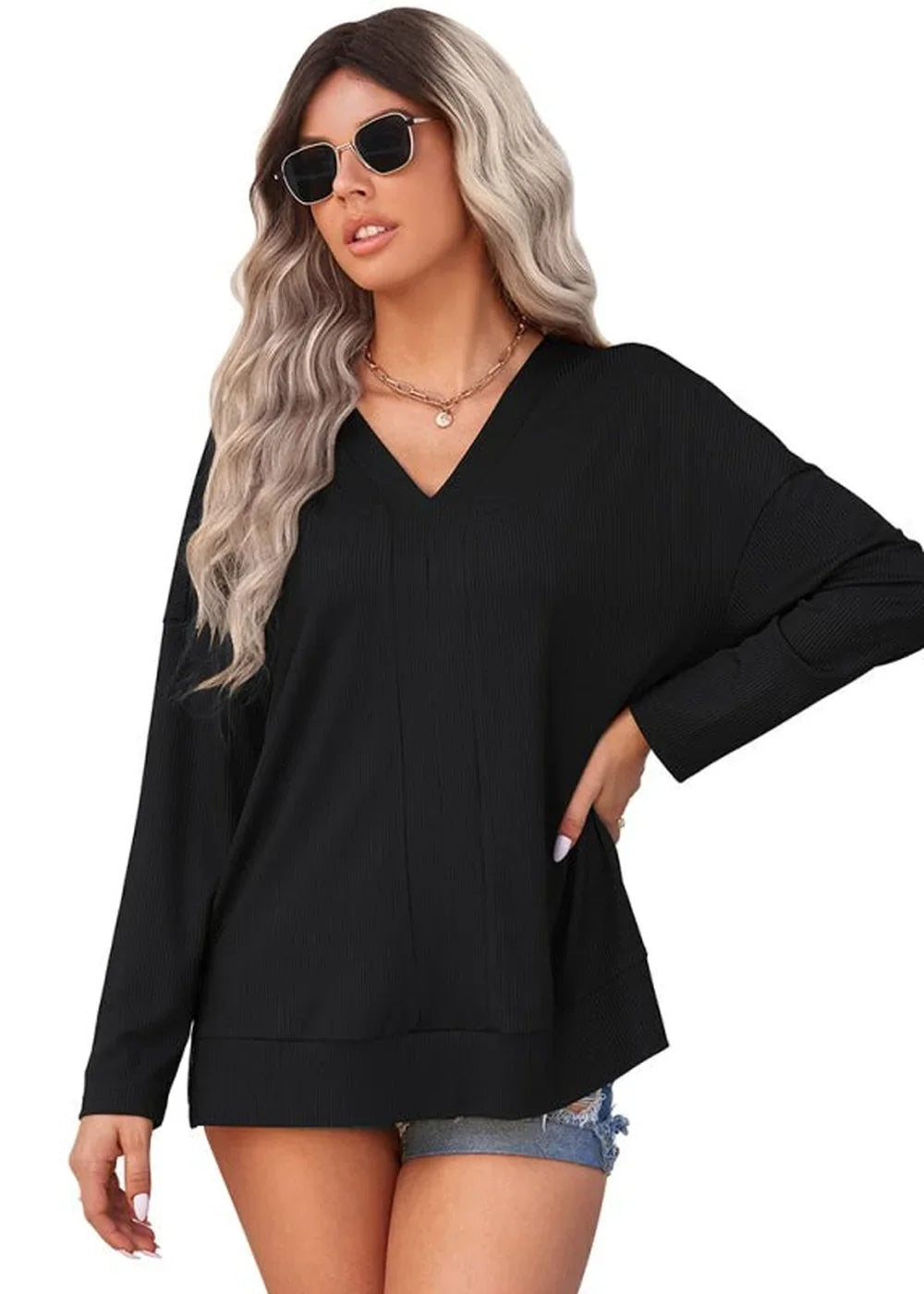 Black long-sleeve V-neck top with ribbed texture on model wearing denim shorts.
