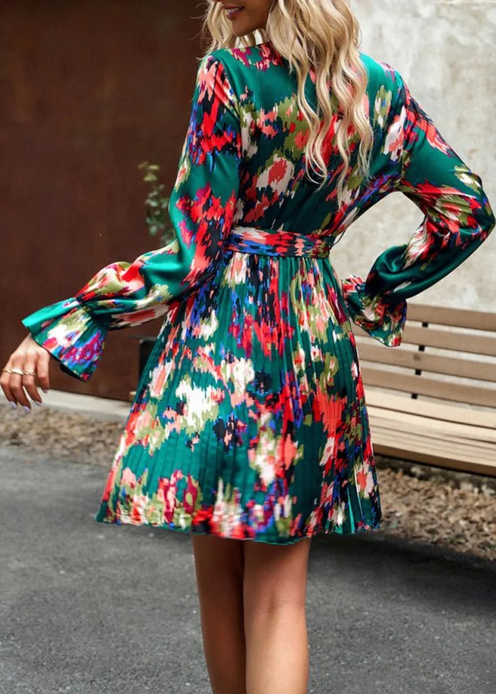 Emerald green mini dress with abstract floral print, pleated skirt, and flared sleeves.