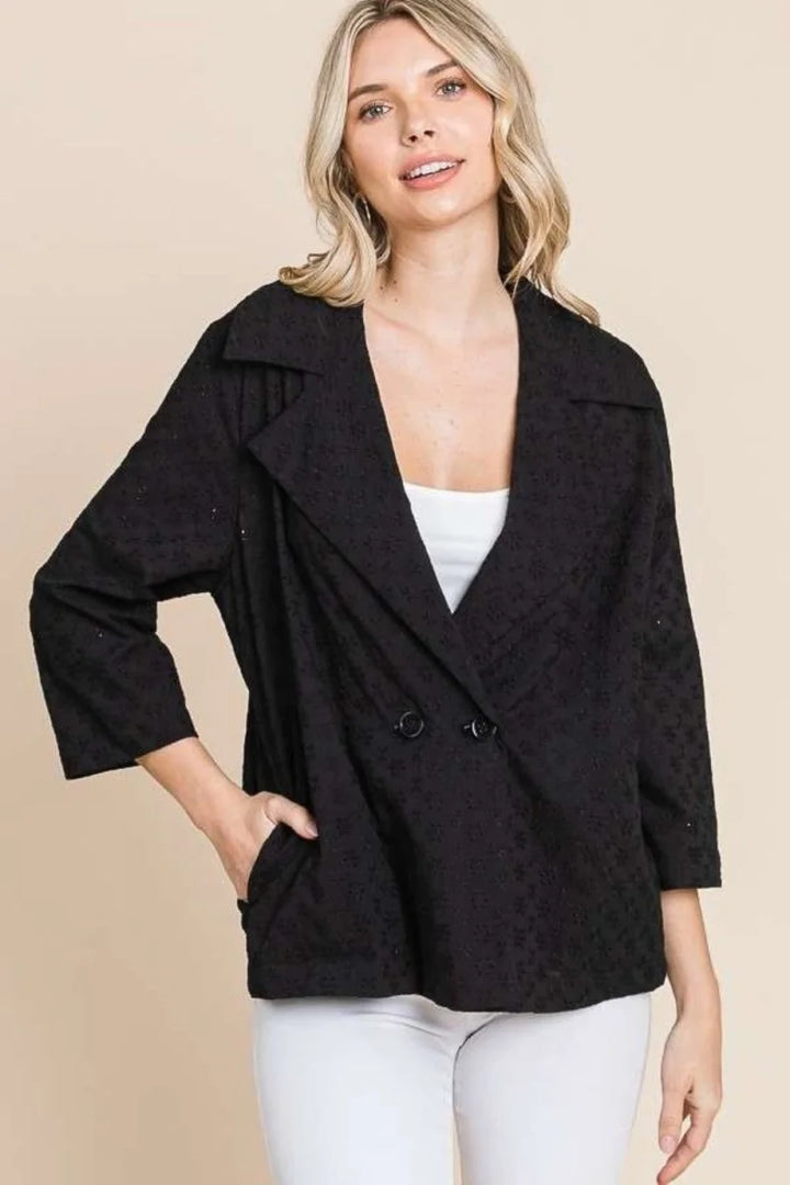 Black double-breasted tailored fit jacket with textured floral pattern and three-quarter sleeves on a model.