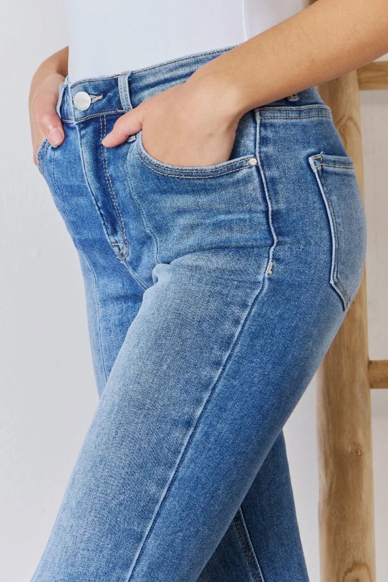 Close-up of light wash distressed denim jeans with pockets and button detail.