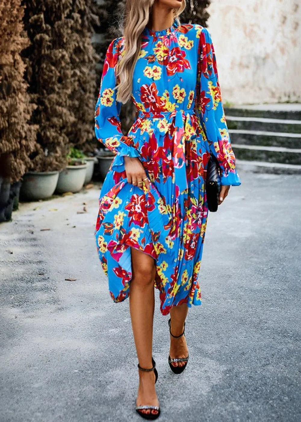 Blue floral print midi dress with ruffled sleeves and a cinched waist, worn with black heeled sandals.