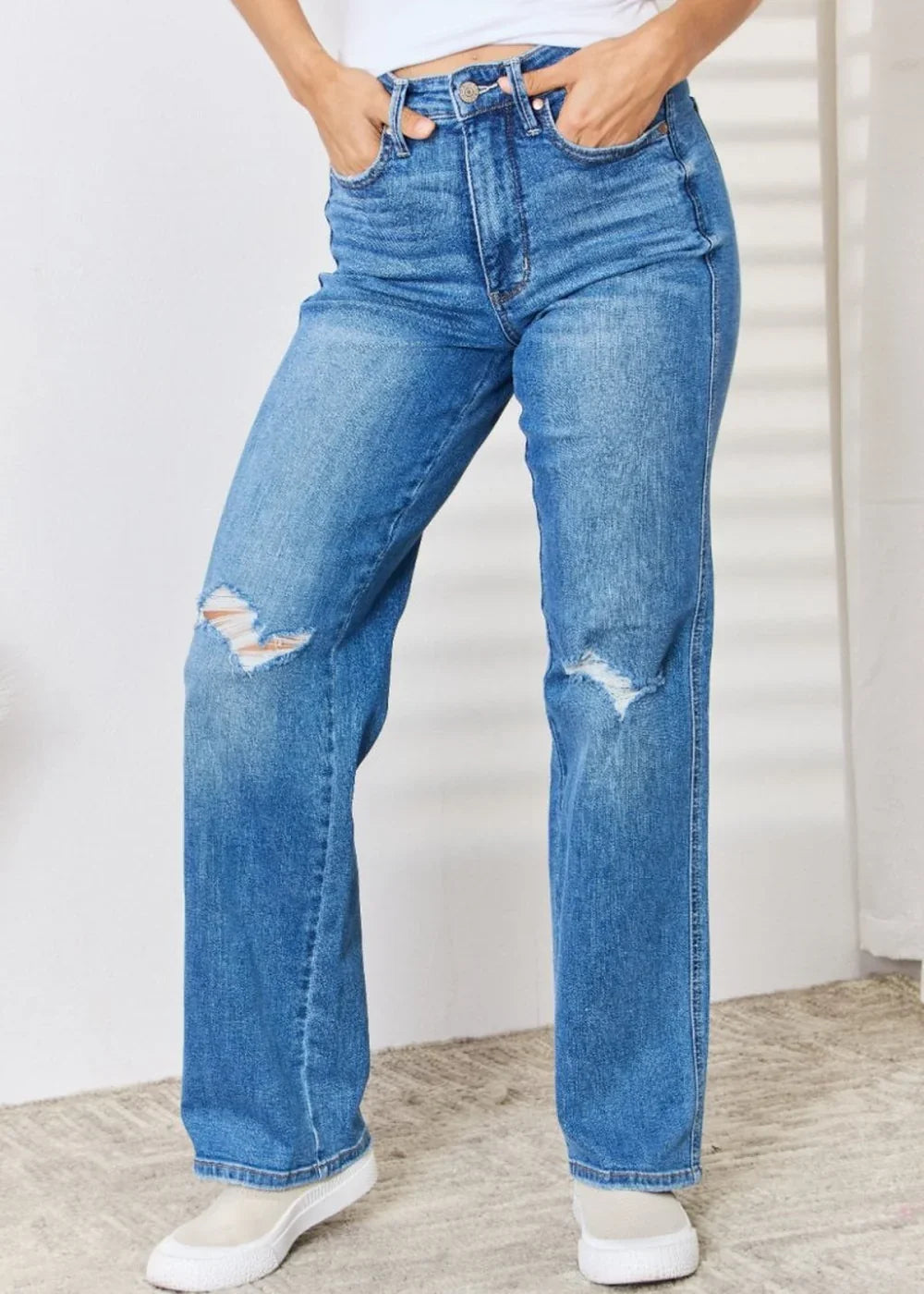 Medium wash distressed denim jeans with a straight leg fit on a model.