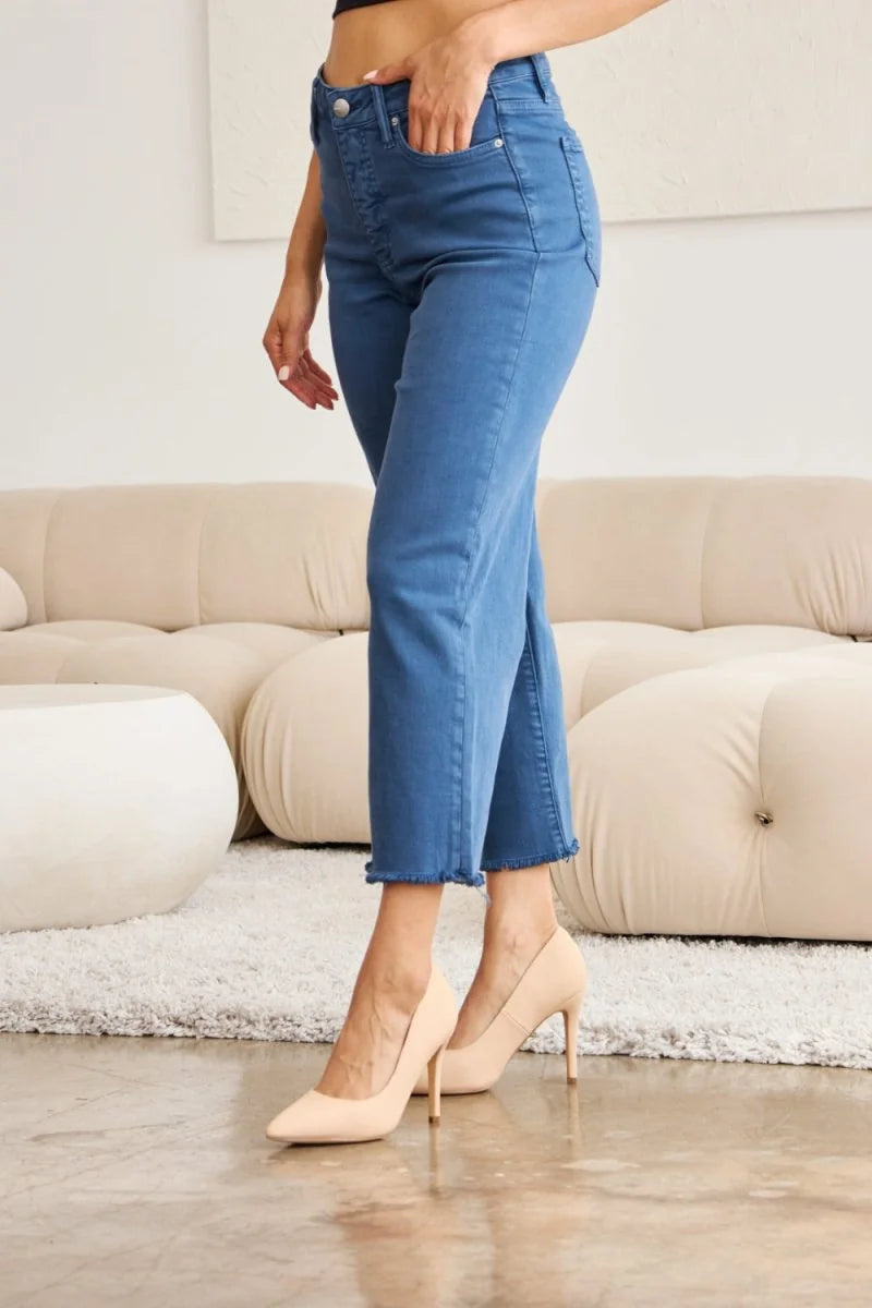 Blue denim jeans with a frayed hem and a regular fit on a model.