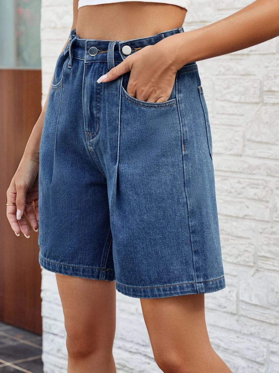 Close-up of medium wash denim shorts with a relaxed fit, featuring front pockets and a clean hem.
