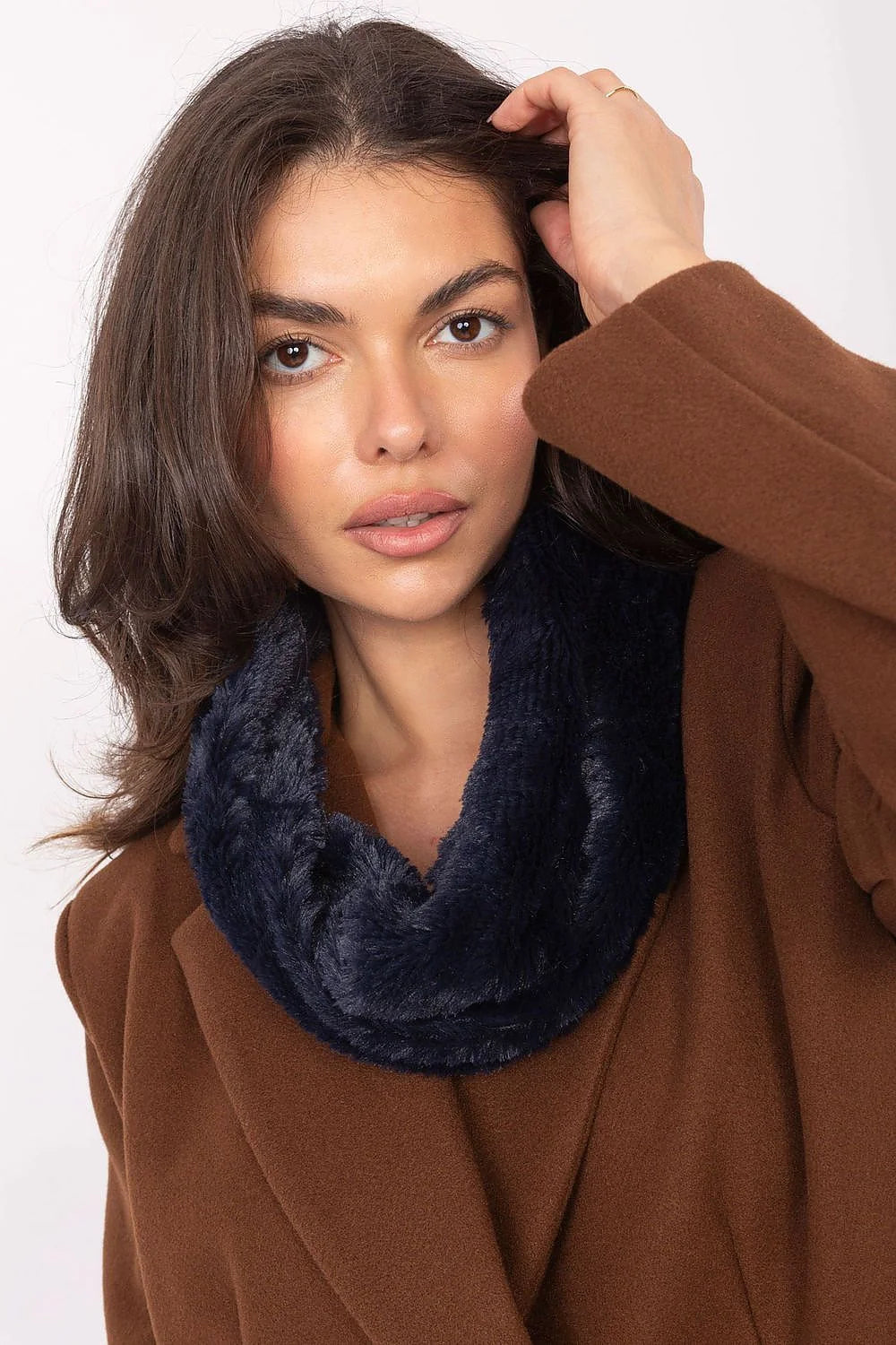 Close-up of a woman wearing a brown coat and a navy blue furry infinity scarf.