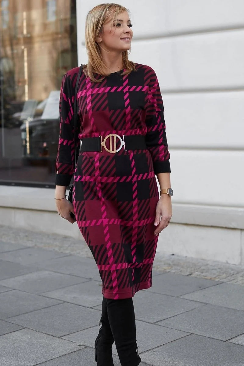 Woman in a magenta and black plaid dress with a wide black belt and silver buckle.