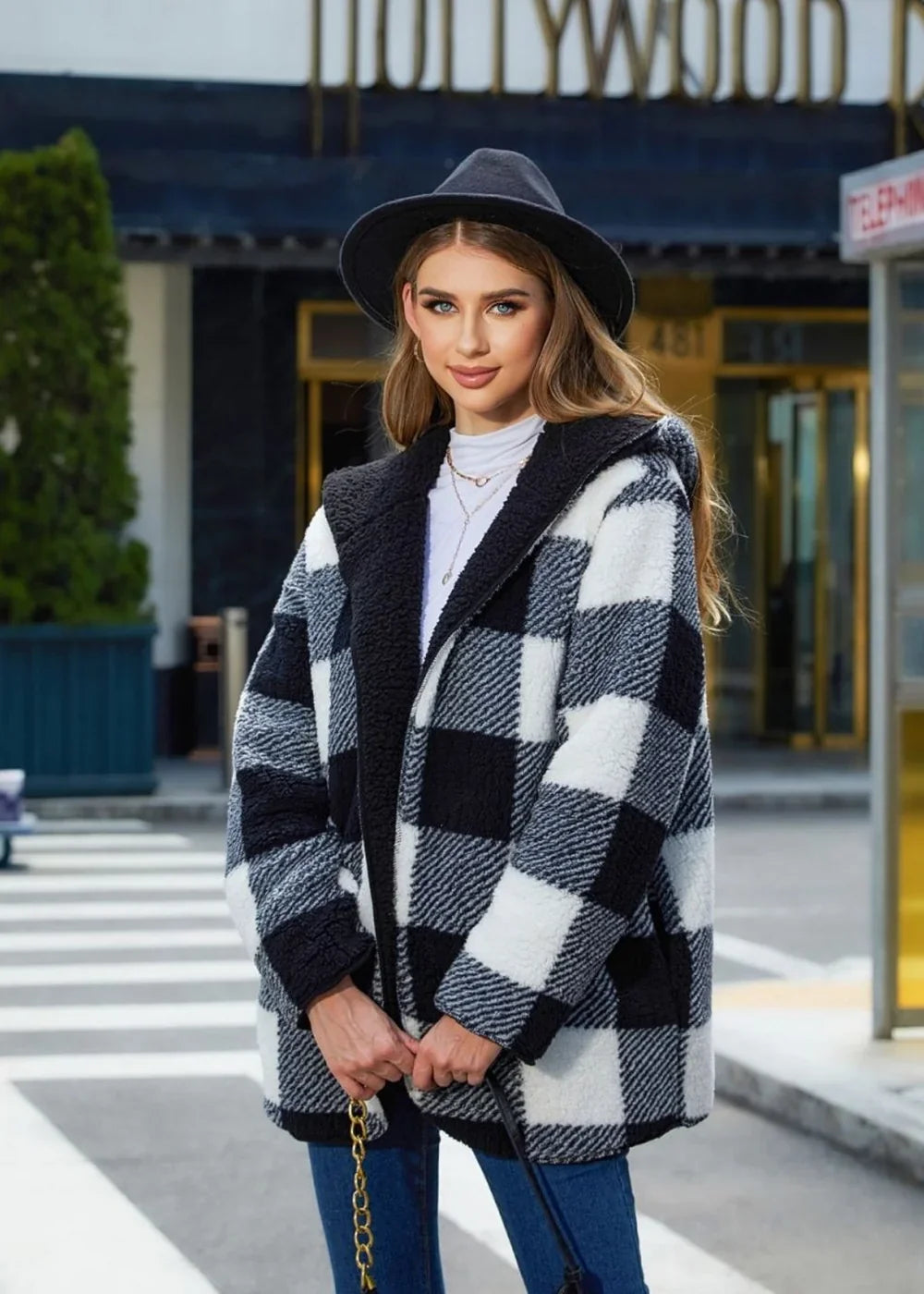 Black and white buffalo plaid sherpa coat with hood on model.