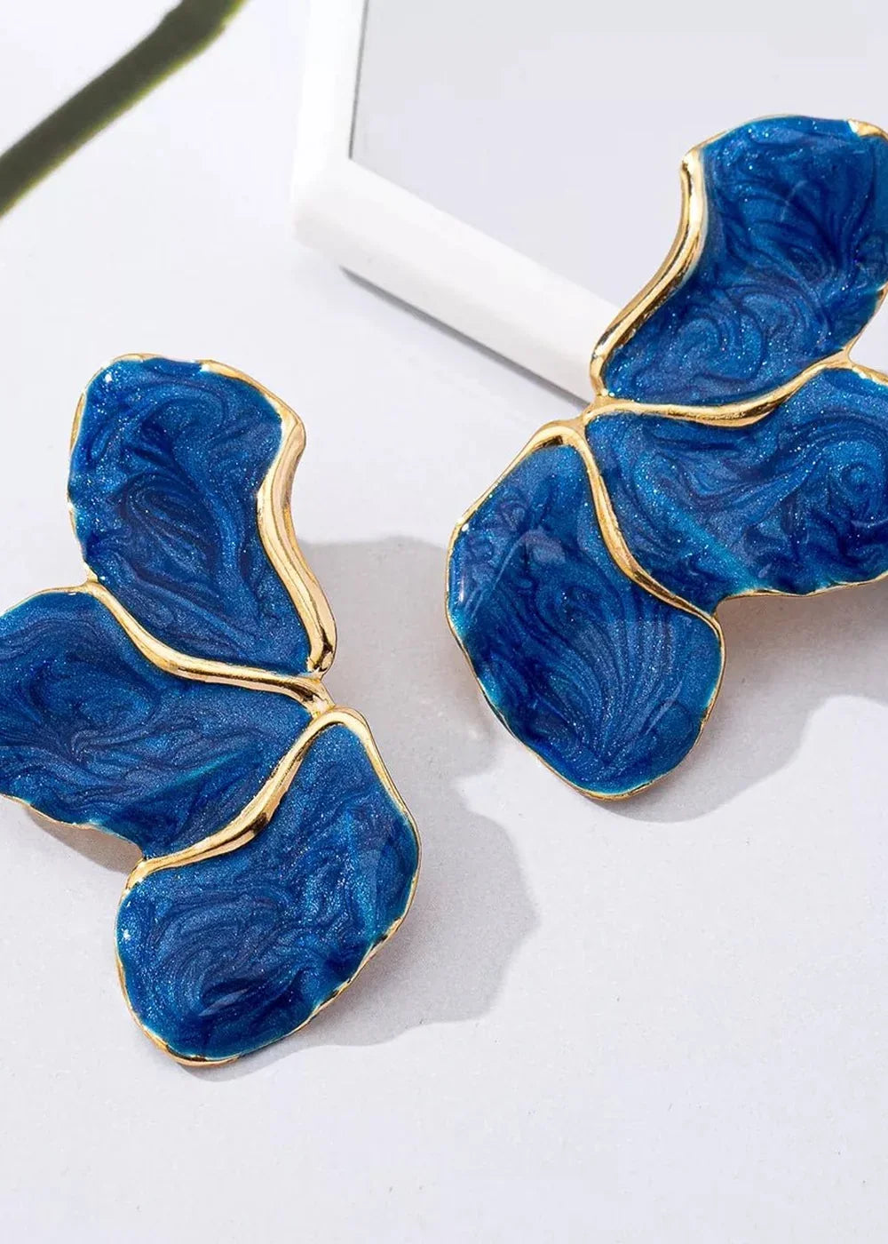 Blue resin earrings with gold trim and a swirling, marbled texture.