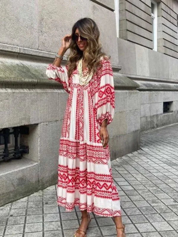 Woman in a flowing white and red geometric print maxi dress with a tiered skirt and statement necklace.