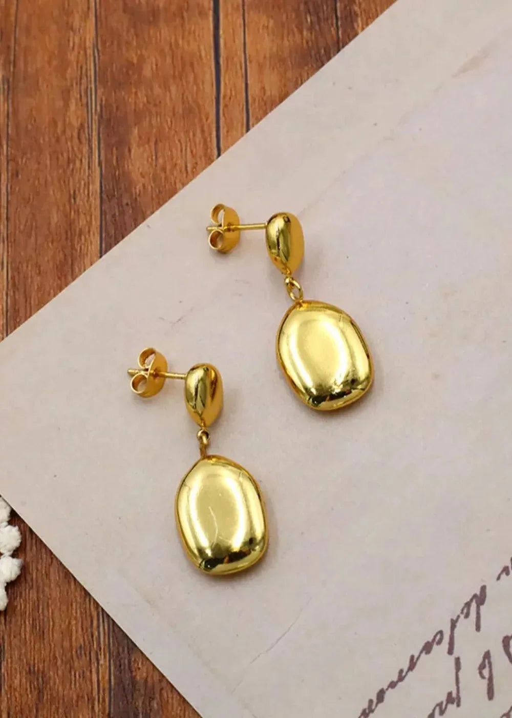 Gold-plated stainless steel drop earrings with smooth, irregular oval pendants.