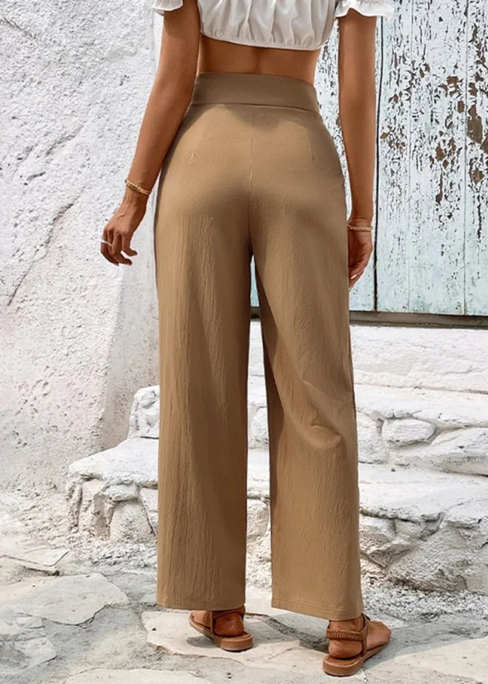 Back view of tan linen-blend wide-leg pants on a model, showing textured fabric and a high waist.