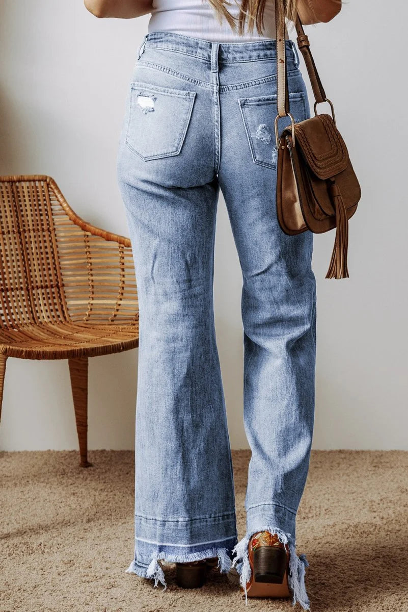 Light wash distressed denim flared jeans with frayed hem and fringe detail.