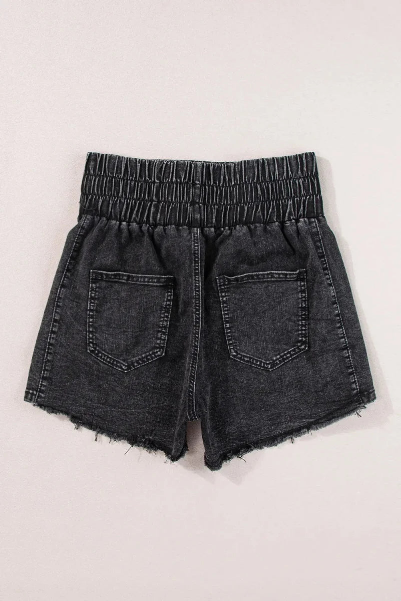 Distressed black denim shorts with a smocked waistband and frayed hem, showing the back pockets.