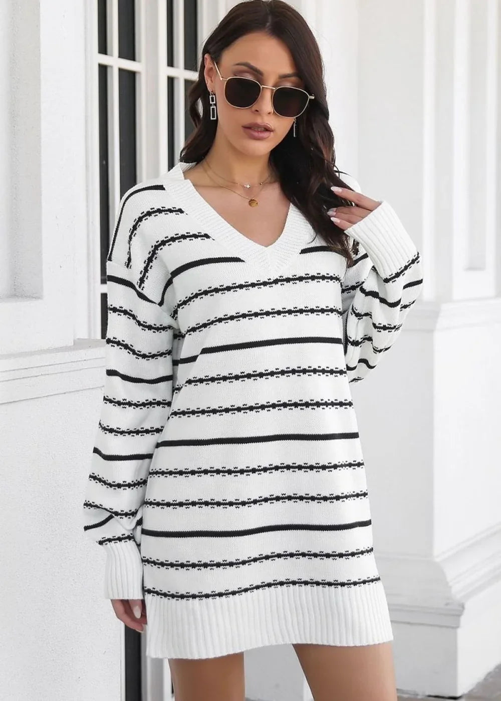 White and black striped V-neck sweater dress with long sleeves on a model.