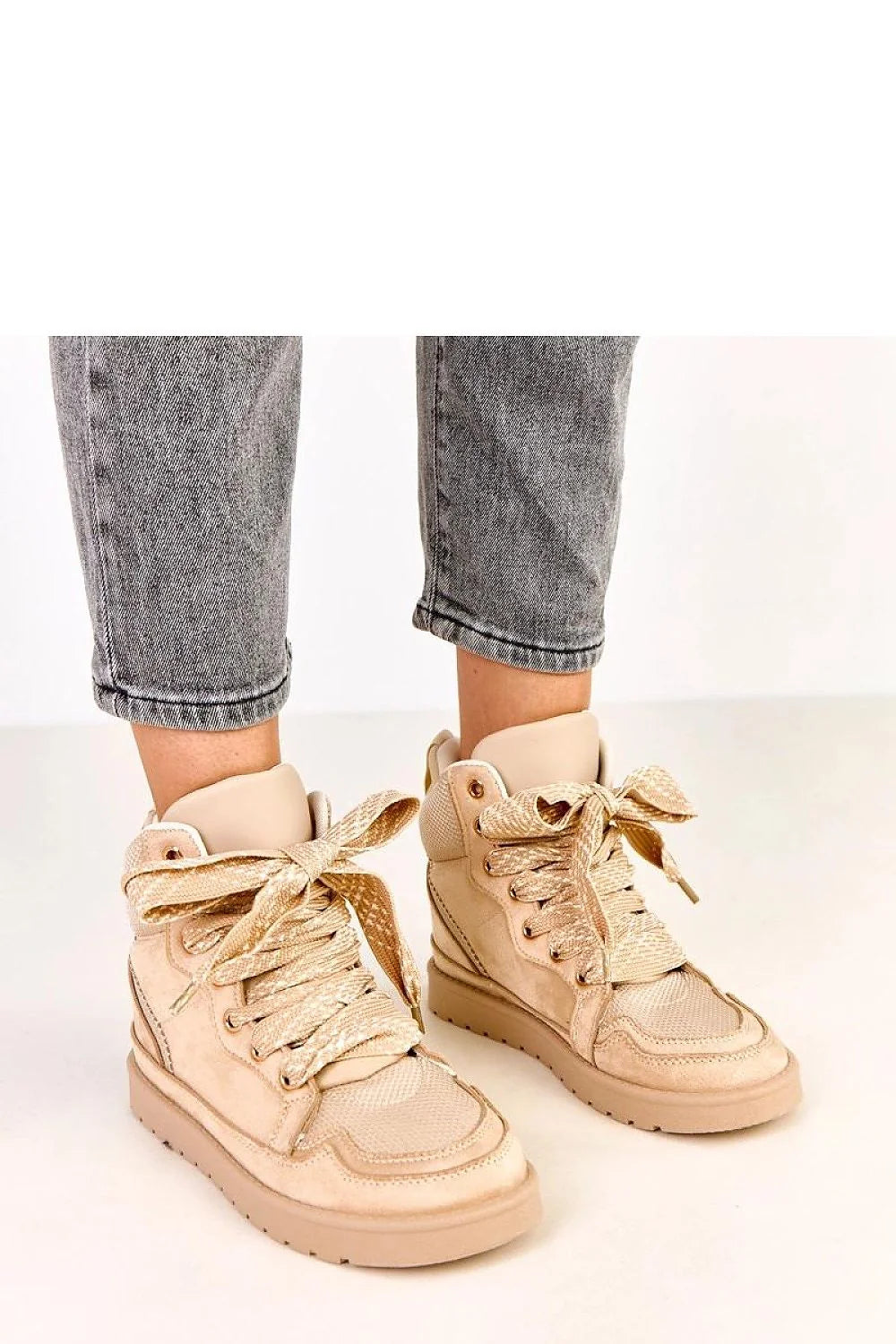 Beige suede-like eco-leather high-top sneakers with oversized ribbon laces on model.