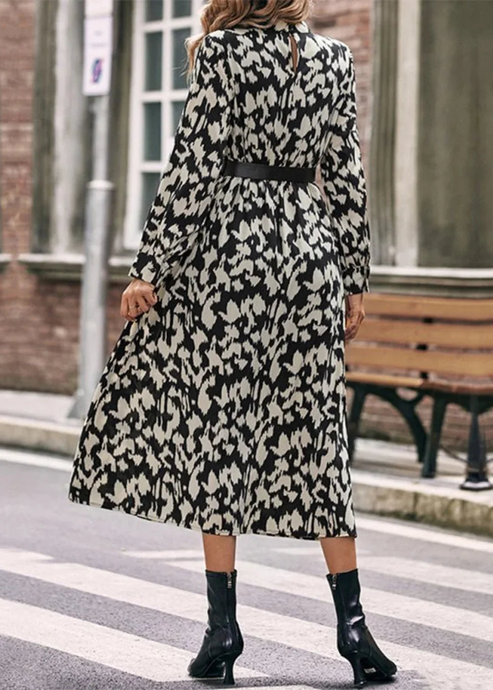 Black and white abstract print midi dress with long sleeves, black belt, and black boots.