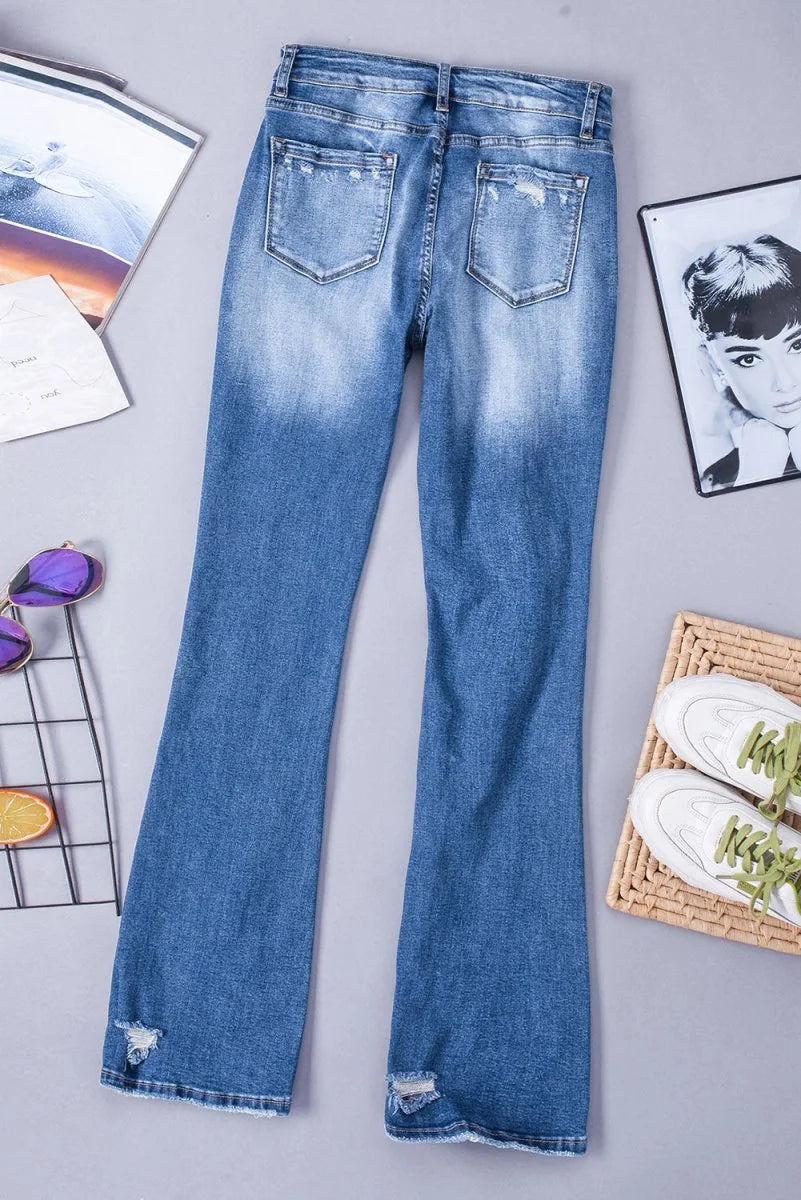 Distressed blue flare jeans with frayed hems and a faded wash.