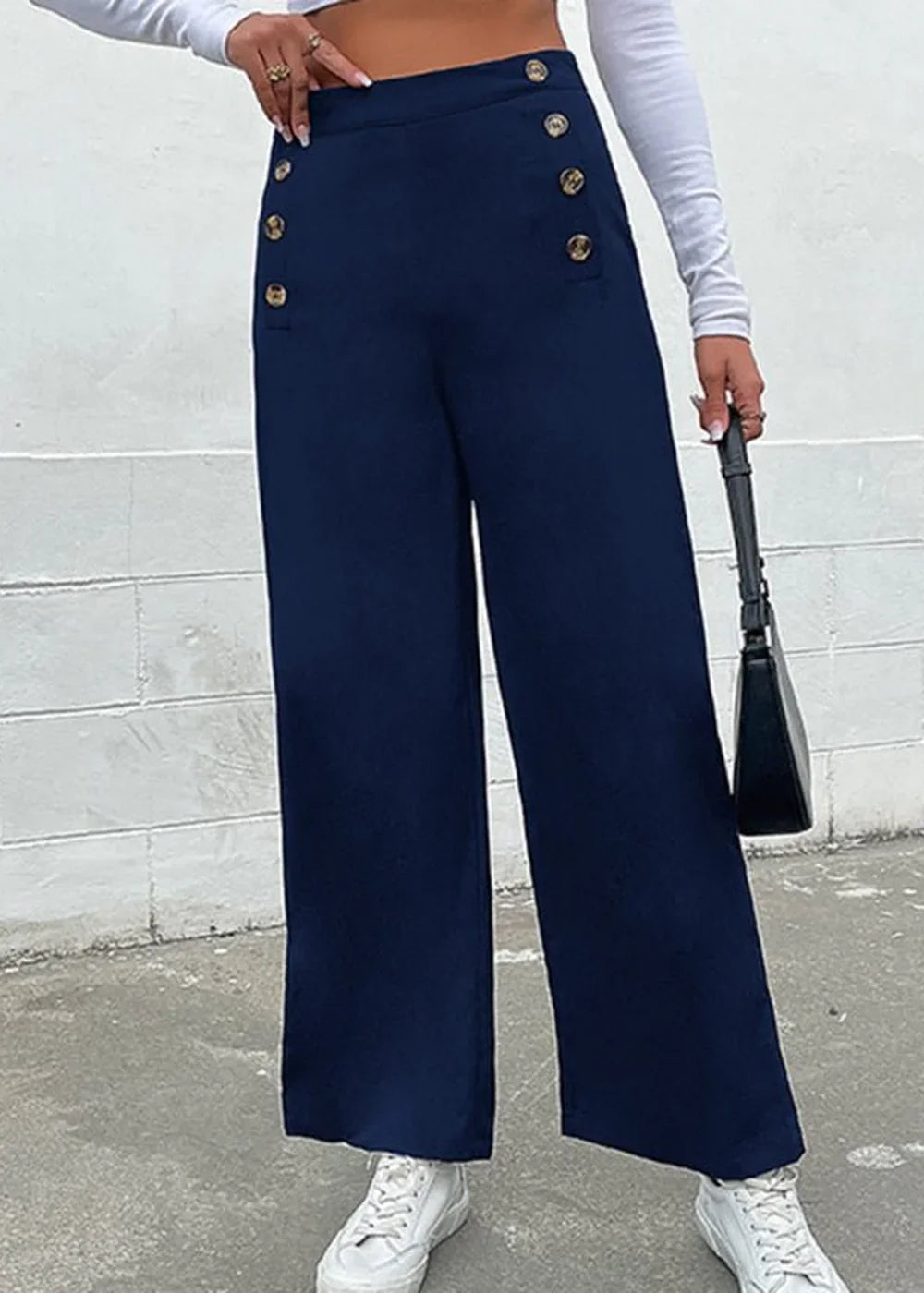 Navy blue wide-leg pants with gold button details and white sneakers.