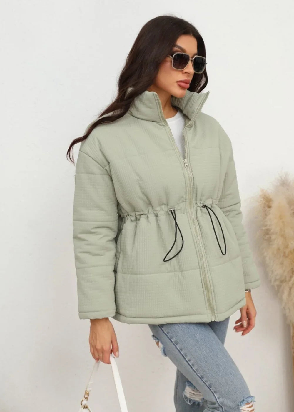 Light green quilted puffer jacket with cinched waist and drawstring, worn by a model.