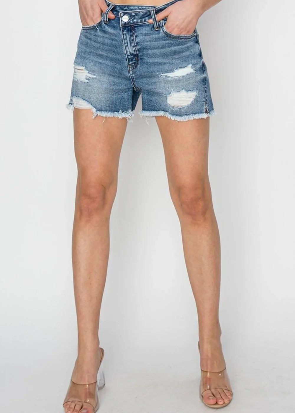 Distressed denim shorts with frayed hem and raw edges on a model, showing a light wash blue.