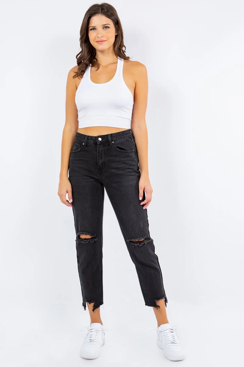 Black high-waisted distressed denim jeans with a frayed hem on a model.