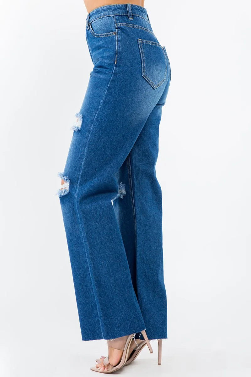 Blue distressed denim wide-leg jeans with frayed hem and clear strap heels.