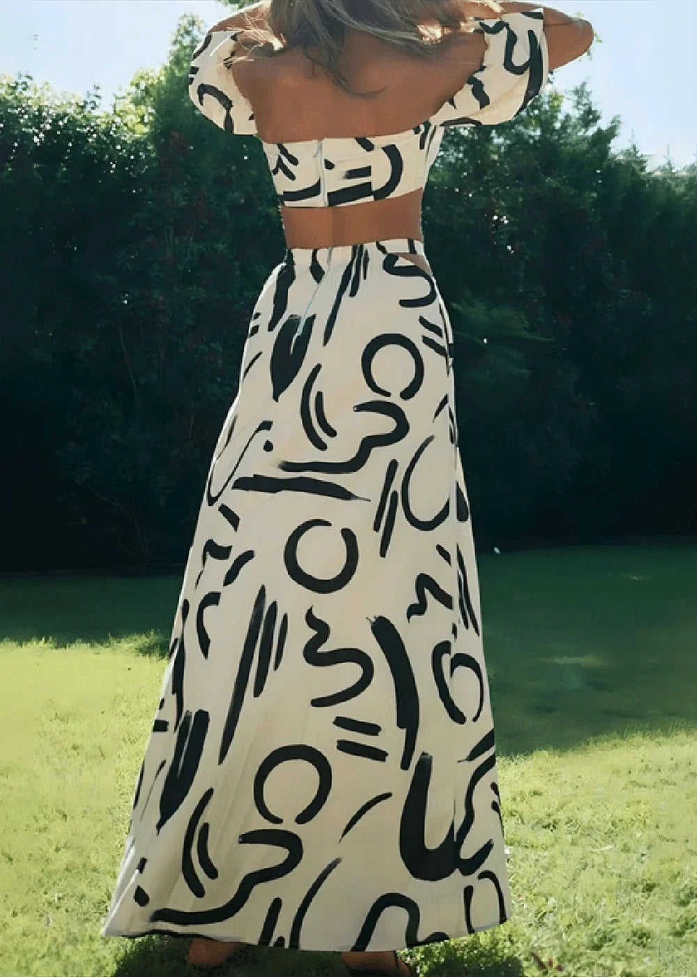 White and black abstract print maxi skirt on model, with a high waist and flowing A-line silhouette.