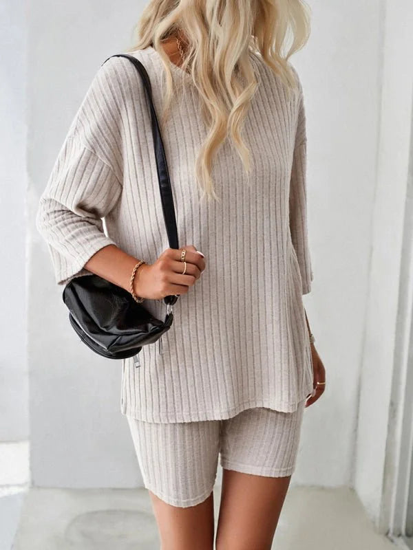 Beige ribbed knit loungewear set with black crossbody bag on model.