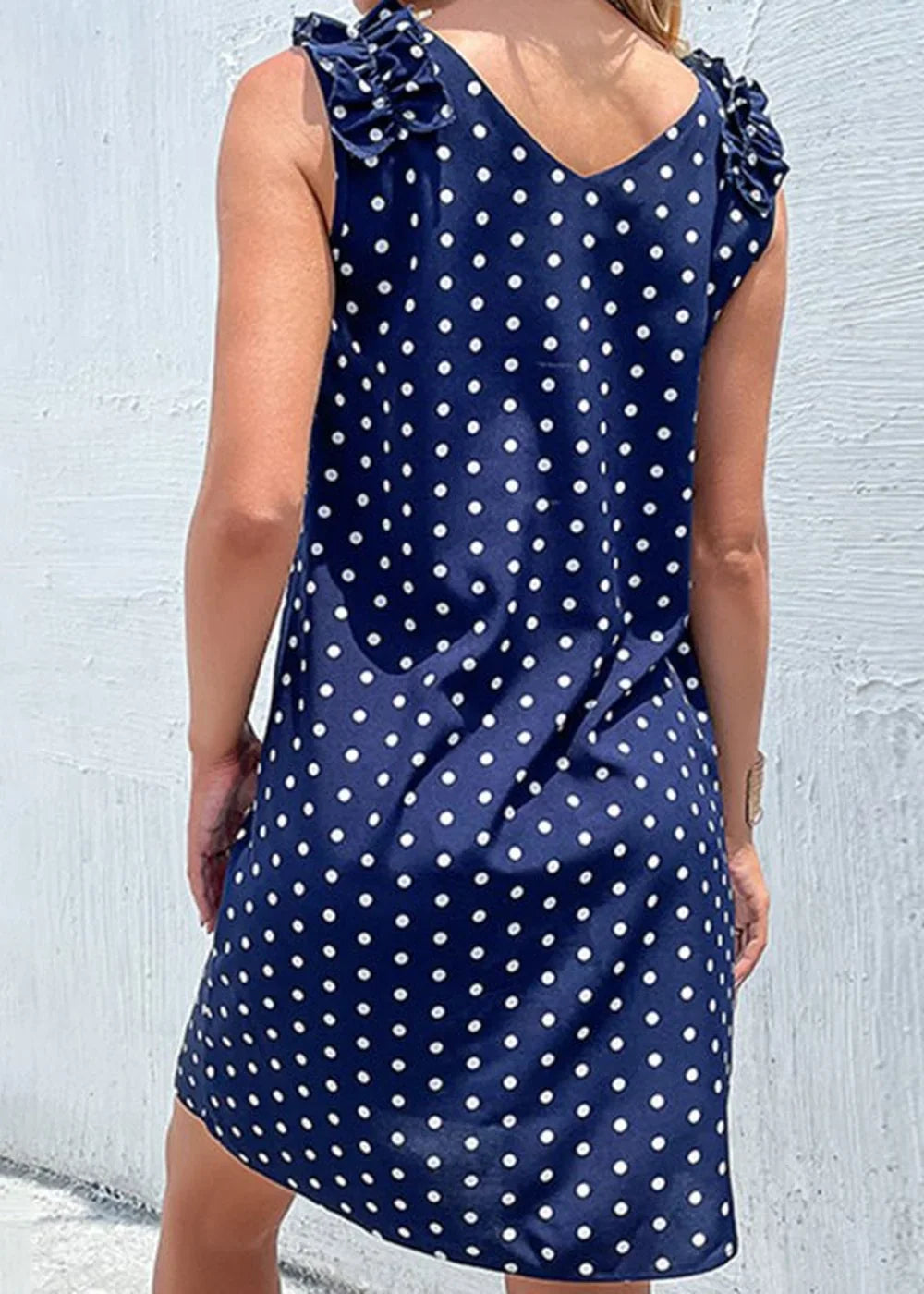 Navy blue polka dot dress with ruffled shoulders, showing back view.