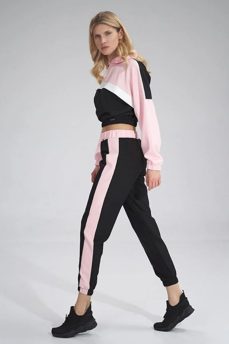Woman in a pink and black tracksuit with pink stripes down the legs and sleeves.