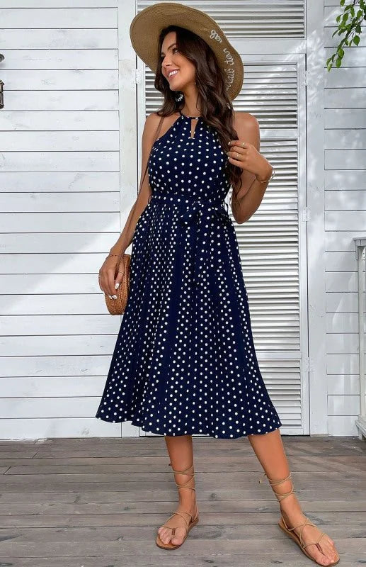 Navy blue polka dot halter dress with a tie waist and strappy sandals.