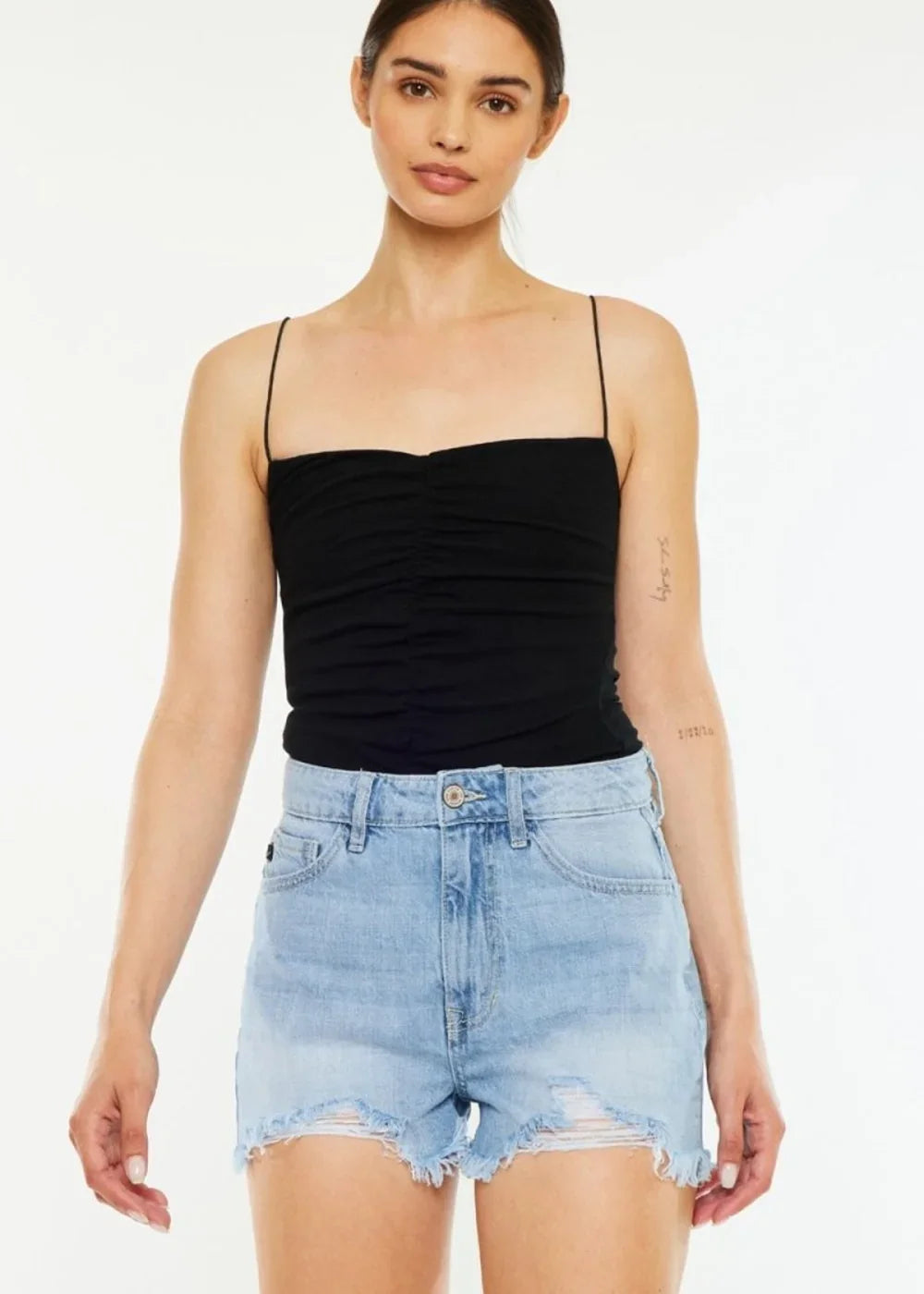 Light wash denim shorts with frayed hem and distressing, on a model.