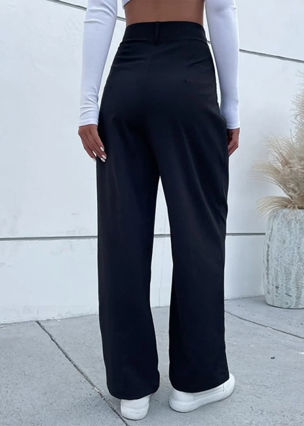 Black high-waisted wide-leg pants made of polyester, shown on a model from the back.